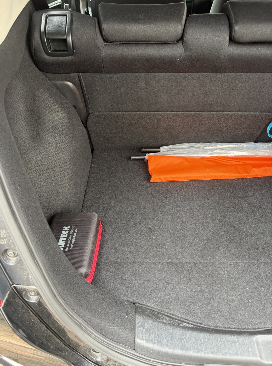 車のトランクの隅に置いたジャンプスターターの専用ポーチ。固定はせず、折りたたみ傘と並べて無造作に置いてあるだけ